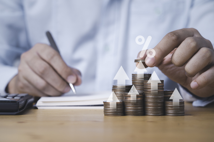 Businessman putting coin stacking with up arrow and percentage sign for increase financial interest rate and business investment growth from dividend concept.